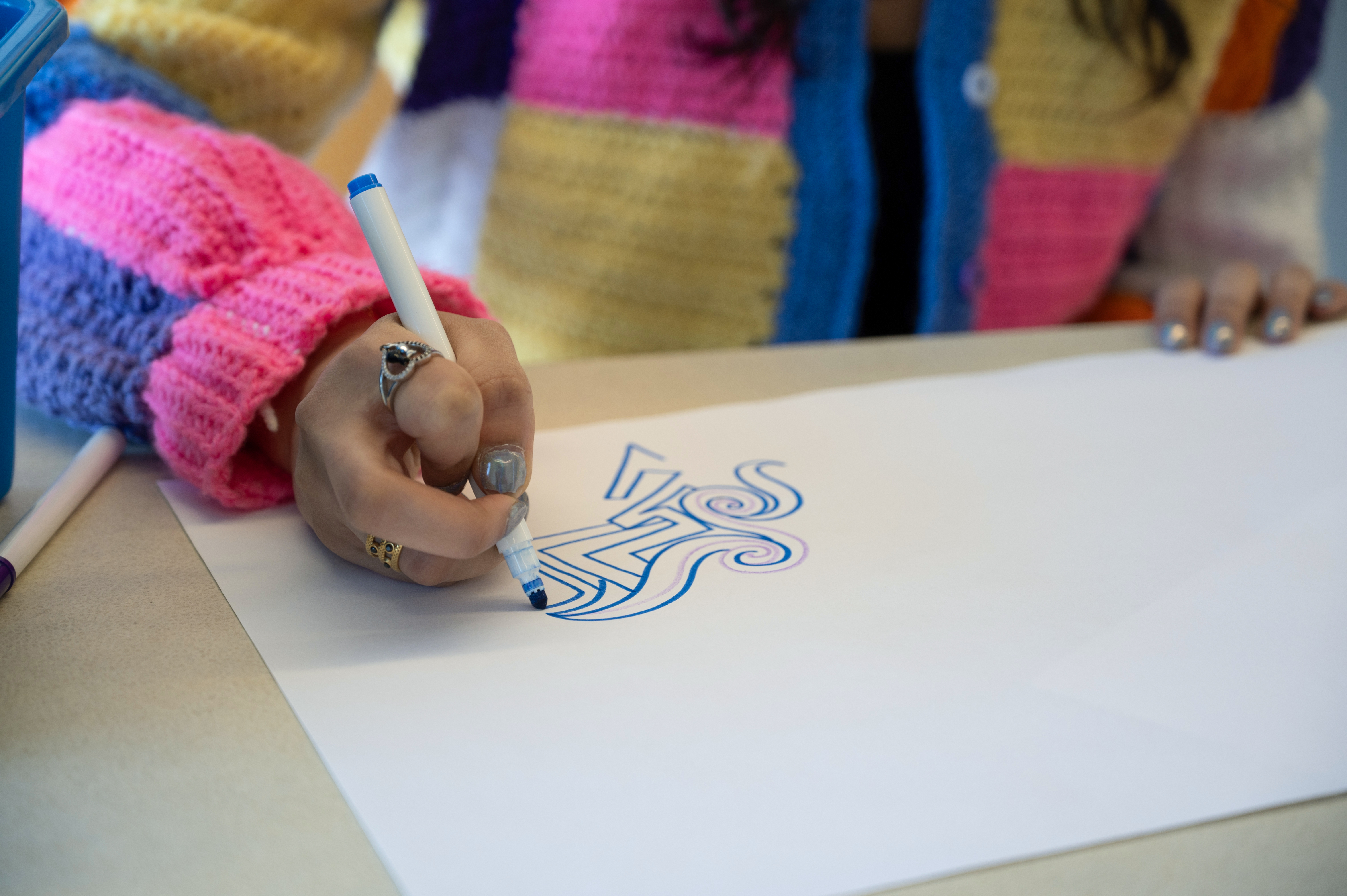 Tara Duggal's hand with a marker, coloring a design